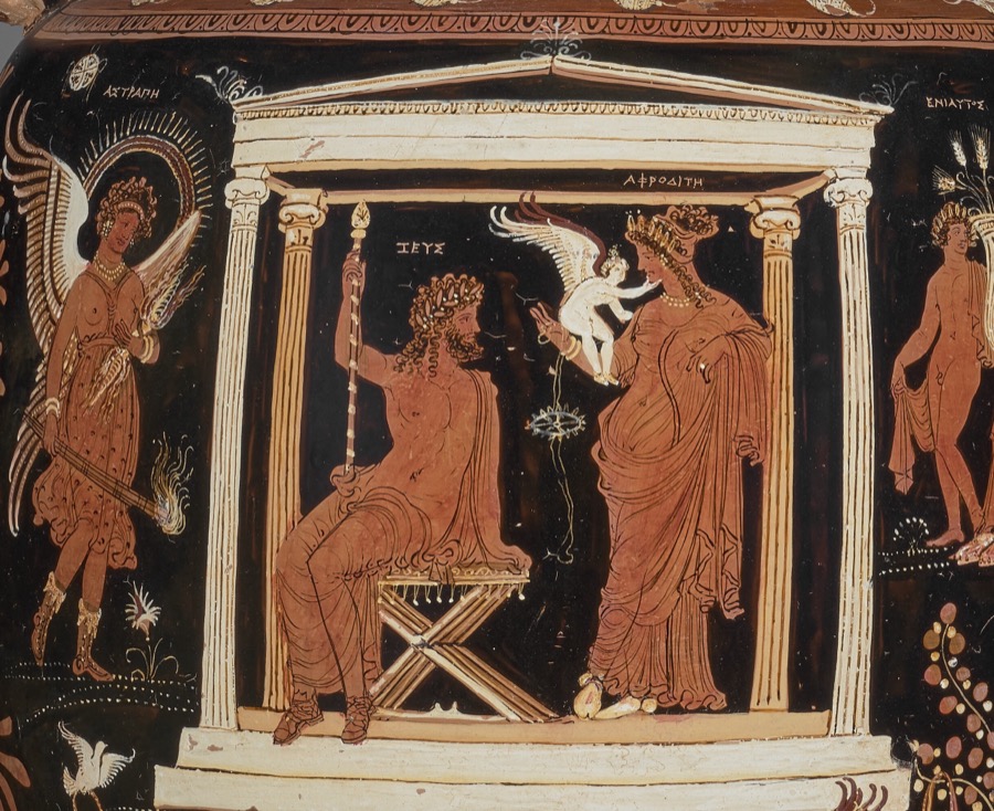 Red-figure vase scene in a white columned shrine: Zeus seated with a sceptre, Aphrodite standing at right, and between them a hovering winged Eros above a small spoked wheel hanging on strings.