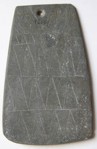 Slate plaque engraved with rows of triangles, its biconical suspension hole drilled at the top, museum inventory number inked below the hole.