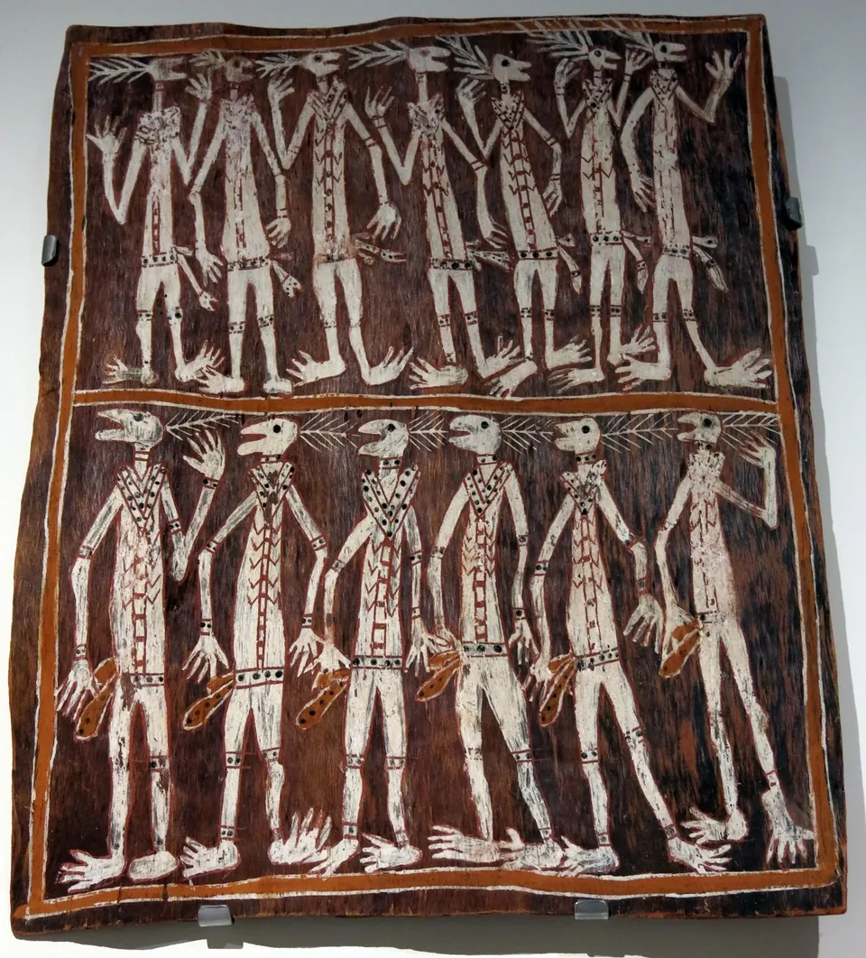 A bark painting of two rows of dancers with long white limbs, open birdlike mouths and radiating head adornments on a red-brown ground.