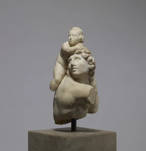 A marble infant Dionysus riding on the shoulder of a satyr.
