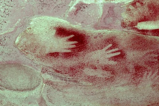 A red-ochre rock-art panel from Kings Tableland with two white hand stencils layered over an earlier painted form; no image of Burgess Point's...
