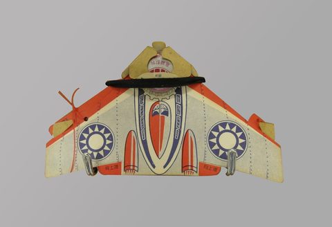 The Tainan bullroarer: a cardboard aircraft on red nylon thread.