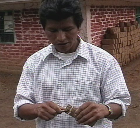 Kisgo zumbador reconstruction, 2005: a man in a checked shirt looks down at the small instrument held between his hands.