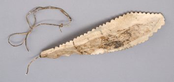 The Chesterfield Inlet plate itself — serrated caribou bone with its single seal-skin cord.