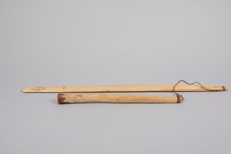 The Carrier (Dakelh) bull-roarer documented here — a pale wooden blade with its slender swinging stick and cord laid alongside.