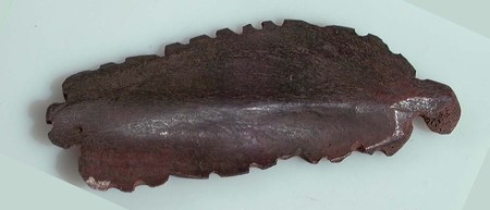 The Hunkpapa Lakota bone bull-roarer documented here — a slat with fine zigzag serration along both edges and a perforation at the narrow end.