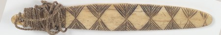 The Karuk incised-bone bull-roarer documented here, its surface covered in a fine diamond chevron pattern, with plant-fibre cord wound at the...