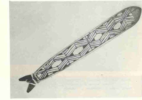 A Kamayurá parapara in Bastos's studio photograph — the lattice-painted blade whose whirring cord ties to a whirling rod.