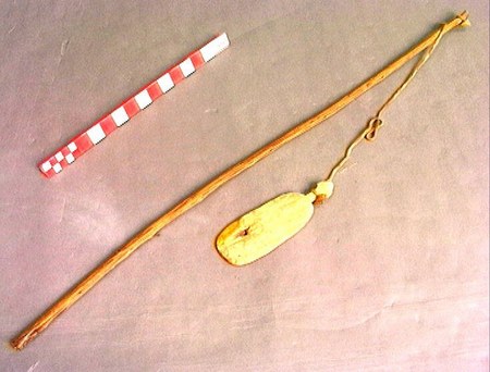 A slender wand strung at one end with a small, leaf-shaped wooden blade on a cord — the Kamoro "bromhout aan stok" whip-style bull-roarer from...