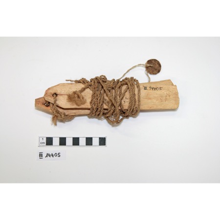 One of the Kassena nàvúni bullroarers collected in Koumbili by Kunz Dittmer in 1956: a flat wooden slat bound to its twisted cord, the cord...