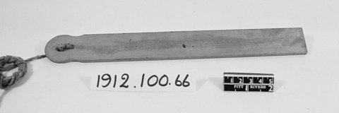 A long, narrow Chichester whizzing blade with a cord knotted through its rounded end.