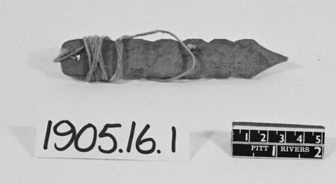 Small carved Bristol bullroarer with a dark tapered blade, scalloped edges and cord wound around its broad end.