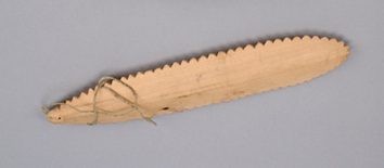The Pelly Bay blade itself — serrated along both edges, its mammal-sinew cord through the terminal hole.