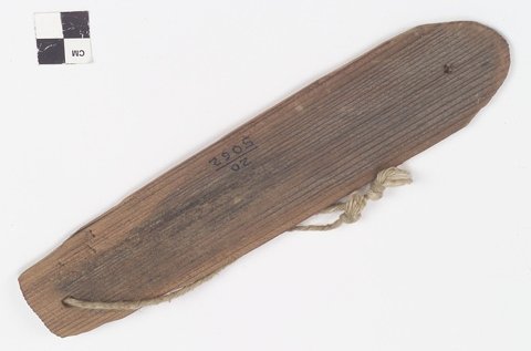 Catawba wooden bullroarer with a long rounded blade and cord threaded through its squared end.