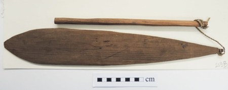 A Nuu-chah-nulth bull-roarer from Vancouver Island — a lens-shaped wooden blade lashed by cord to its swinging handle rod, collected in 1912;...