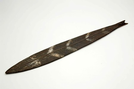 A dark wooden blade incised with white cross-hatched bands and a small notched tip, from the same Netherlands New Guinea collection; the...