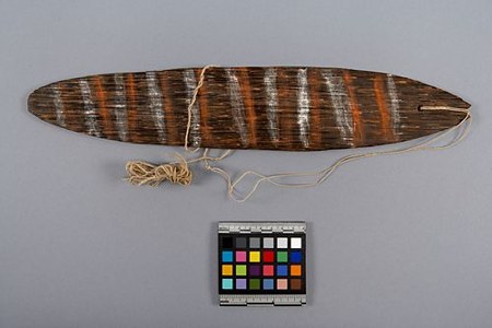 The sova itself: a dark wooden blade with a braided cord, its face carved with diagonal painted striping, from Sirorata village in Oro Province.