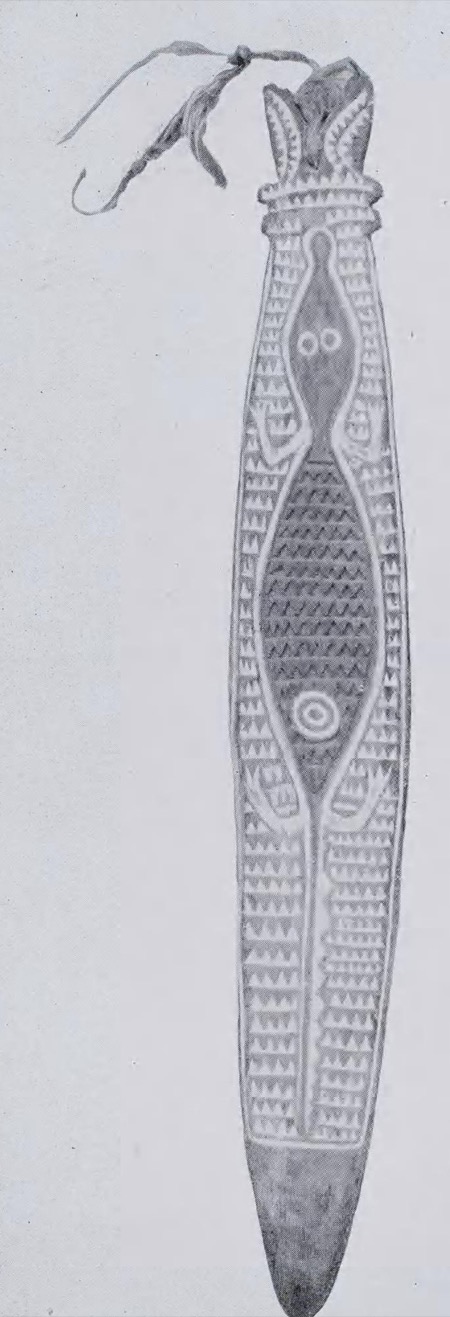 An Orokolo bull-roarer, 668 mm long, its swing-cord still knotted at the head — the front carved with the crude figure of a reptile, probably a...
