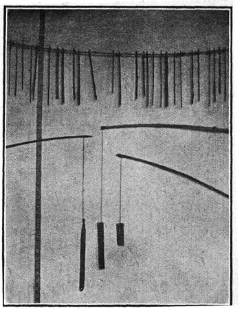Roy's own photograph of Oraon bull-roarers of three sizes, suspended by their handles from a crossbar in the youth dormitory he documents.