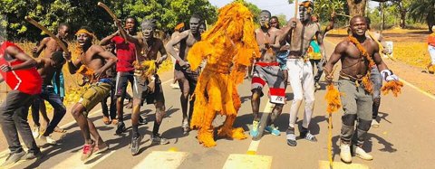 The kankurang, the lodge's masked spirit, with its machete-bearers.