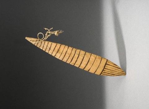 A pale, leaf-shaped Kereboro blade with repeated dark transverse bands and a cord loop through its narrow end.