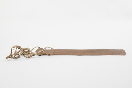 The Dyak hantu-hantuan itself: a flat wooden slat pierced at one end, with a single cord threaded through the hole.