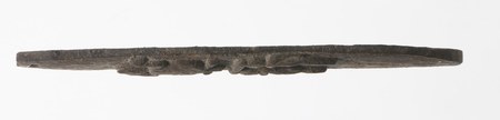 The Gabonese bromhout itself: a long, dark, weathered wooden blade with a raised relief rib running down its face.