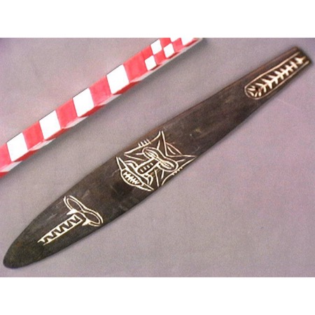 The Tami bullroarer RV-746-38 itself: a narrow carved wooden blade, collected before 1889, with white lime designs and a terminal cord hole.