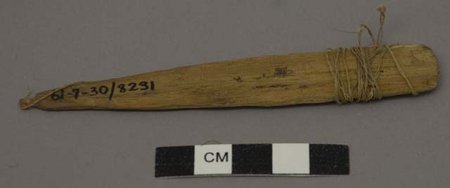 Canela wooden blade, Harvard Peabody 61-7-30/8231, with a cotton tie wrapped around one end and a small loop at the other; a centimeter scale sits below.