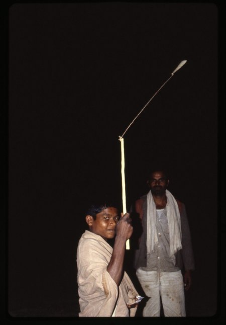 An Abujh Maria boy in Bastar, 1979, whirling a blade on a long cord from a pole tip to scare birds off the crops.