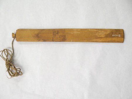 Bamboo mumu from Baguia, Timor, with a small incised bird near the middle and a twisted cord tied at one end.
