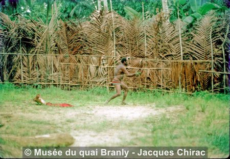An initiator swings the bullroarer inside the palm-frond enclosure at Serangwandu, Wosera, 1973.