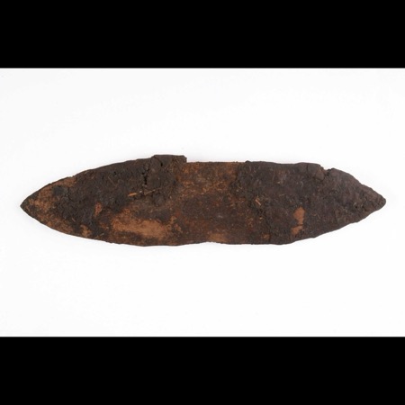 The Boli blade as kept: wood almost vanished under its crusted sacrificial coating.