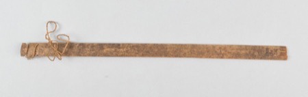 A long, plain wooden lath with a loop of cord tied near one end: an African bullroarer of the general type, not the Teke rhombe documented here.
