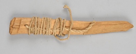 A wooden blade with cord wound around its middle and a loose hank trailing toward the tip — a generic type, not the baranga whirled at night...