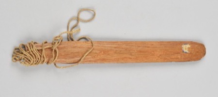 A plain wooden board wound with cord near a small drilled hole: an African bullroarer of the general type, not the Babali (Bali) instrument of...