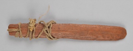 A plain wooden board wrapped with cord near one end: an African bullroarer of the general type, not the Babira (Bira) instrument documented here.