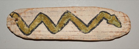 A pale, whitewashed wooden slat with rounded ends, painted with a bold black-outlined zigzag in olive green — snake-like, a blunt head at one...