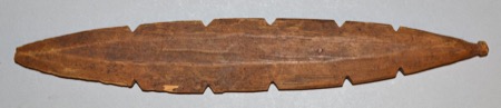 A leaf-shaped wooden blade with widely spaced notches cut along both edges, one tip drawn out to a small stub — a North American bull-roarer...