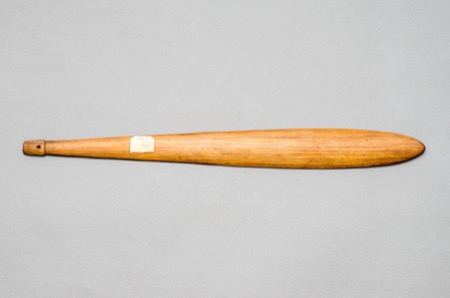 A plain, unengraved New Guinea bull-roarer blade with a drilled hole at the handle end; a generic specimen, not the Tolai object documented here.