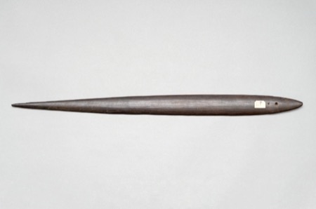 A plain, unengraved New Guinea bull-roarer blade with two small holes drilled near one end; a generic specimen, not the Titans object...