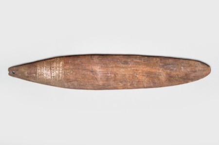 A long, tapering wooden blade left mostly plain but for a band of fine incised triangles near the pierced end - a generic New Guinea...