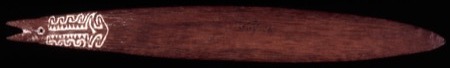 A long dark red-brown bull-roarer blade, one end cut into a fish-tail fork with the cord hole drilled at its base and a panel of lime-filled...