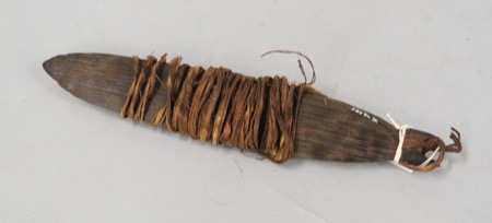 An Abelam bull-roarer, a dark pointed blade with most of its length wound round in plant-fibre cord, tied off at the grip; not the Wogeo object...