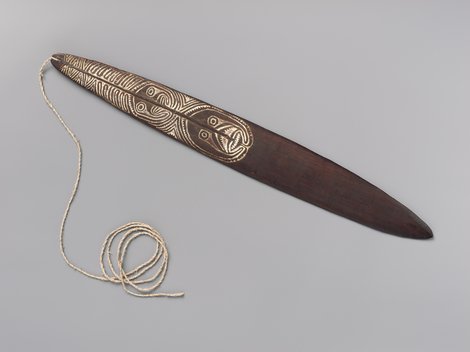 A dark wooden blade painted with fine white featherlike striping near its pierced, corded end — shown for the general Gulf of Papua form, not...
