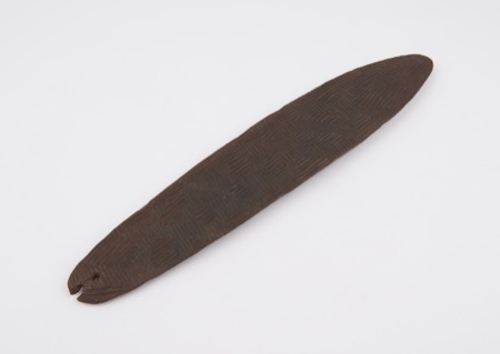 A wooden board carved in a herringbone pattern and pierced at its point — a generic specimen, not the stone yeenma recorded by Daisy Bates for...