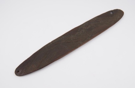 A wooden board carved in a fine herringbone pattern and pierced near its point — again a generic Aboriginal Australian type, not the Derby...
