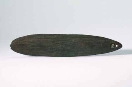 A plain oval Aboriginal Australian bullroarer, its surface finely striated and pierced with a single hole at one end — shown for the general...