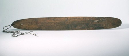 An Aboriginal Australian bullroarer densely engraved with crosshatched diamond patterning, cord looped through the perforated end — a generic...