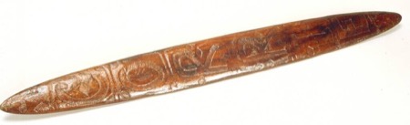 A wooden board carved end to end with concentric scrolls and key-pattern panels, unpierced at either point — a generic Aboriginal Australian...